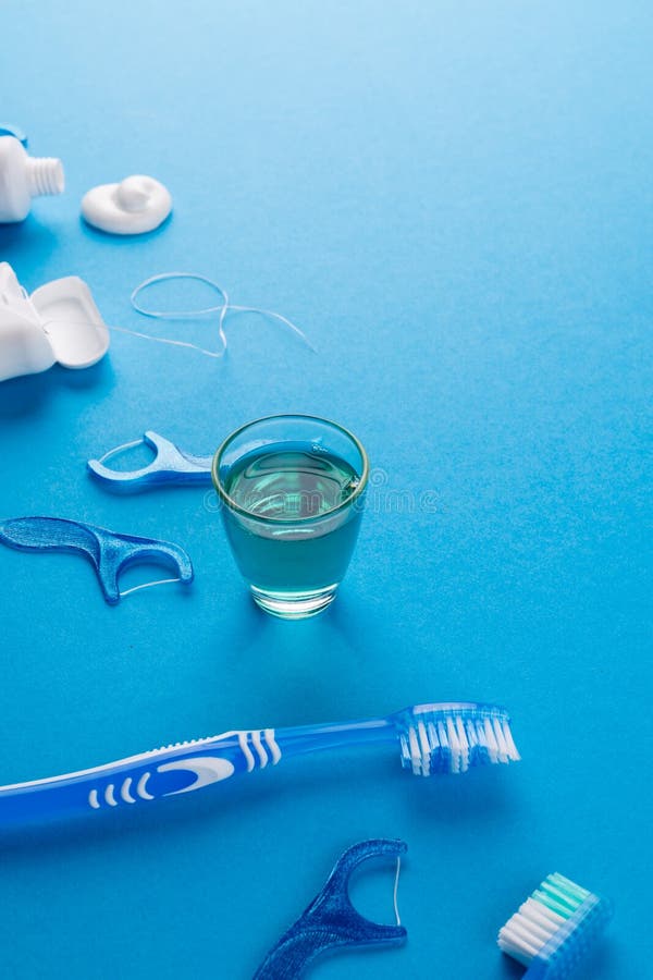 Vertical image of toothbrush, toothpaste, string and liquid on blue surface stock photos