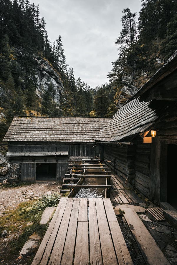 Vertical photo of a beautiful wooden cabin deep in the forest - Mlyny Oblazy Slovakia. Old wooden mill with rocks on background