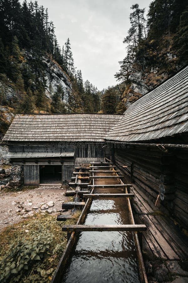 Vertical photo of a beautiful wooden cabin deep in the forest - Mlyny Oblazy Slovakia. Old wooden mill with rocks on background