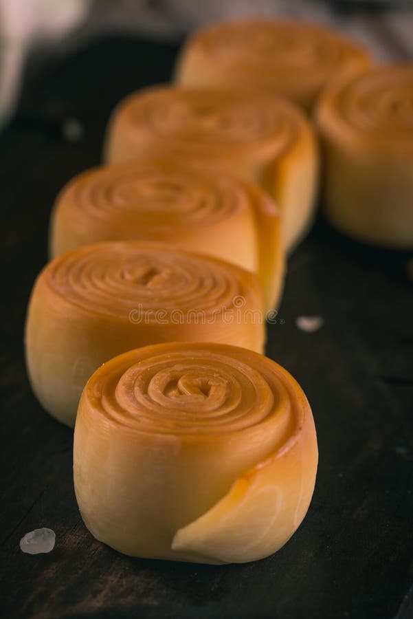 Row few smoked cheese rolls on dark wooden board