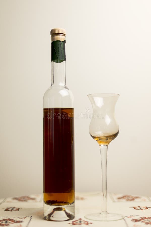 Bottle of amber colored fortified wine with tulip shaped cordial glass. Vertical photo of tall thin bottle of amber colored fortified wine with tulip shaped stock photography Bottle of amber colored fortified wine with tulip shaped cordial glass. Vertical photo of tall thin bottle of amber colored fortified wine with tulip shaped stock photography
