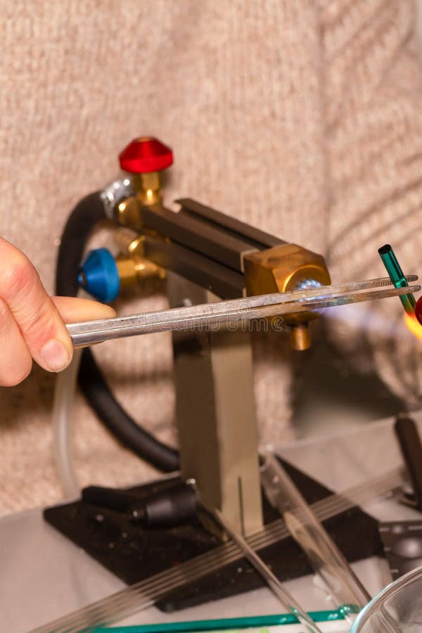 Vertical photo the work of the master glassblower tweezers melted glass warming up the flame of fire stock photos