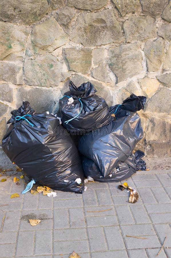 Vertical Picture of Three Black Trash Bags Under the Sunlight Against a