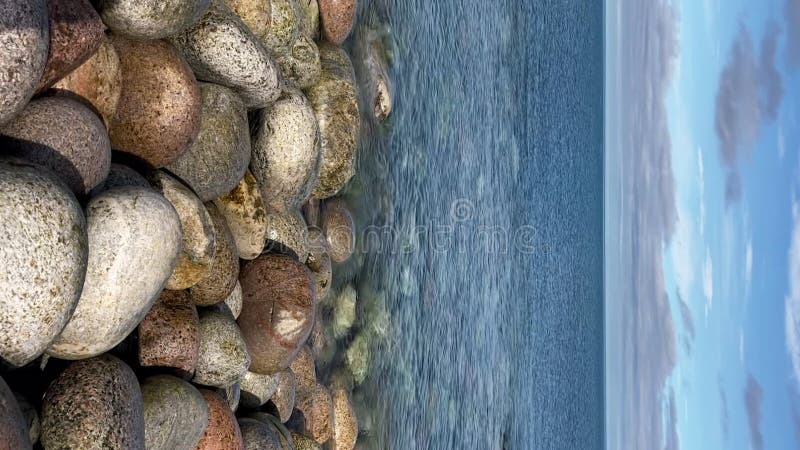 Vertical : pierres arrondies sur la côte nord eau calme