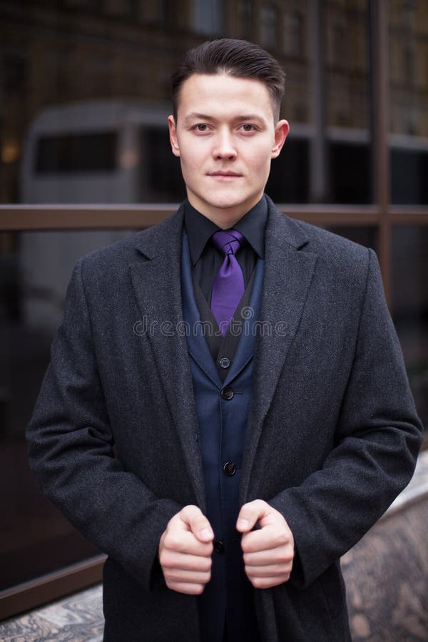 Vertical portrait of a young businessman in suit and coat confidently looking forward stock photo Vertical portrait of a young businessman in suit and coat confidently looking forward stock photo