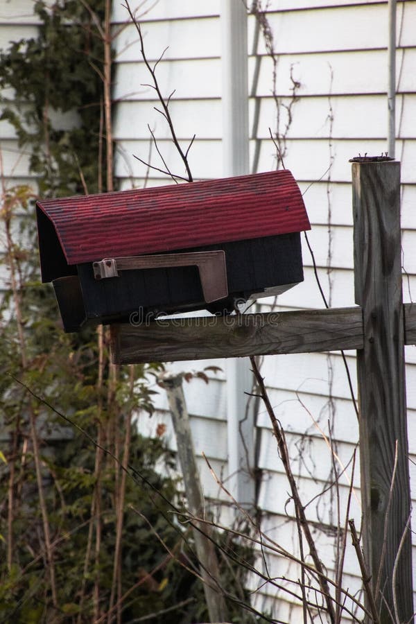 Vertical of a Red Vintage Mailbox on a Wooden Pillar Stock Image