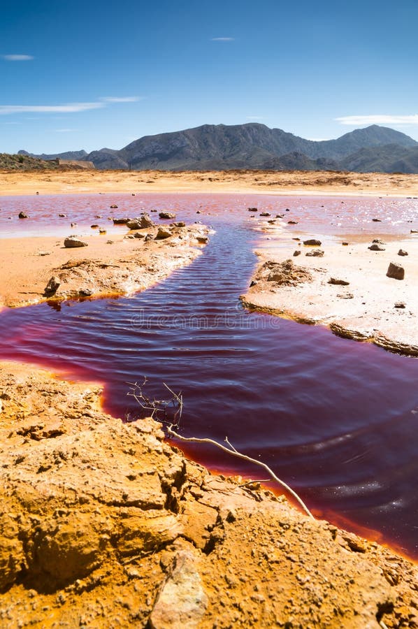 Vertical shot of dark red water flowing in a desert near an old mine in Mazarron, Spain