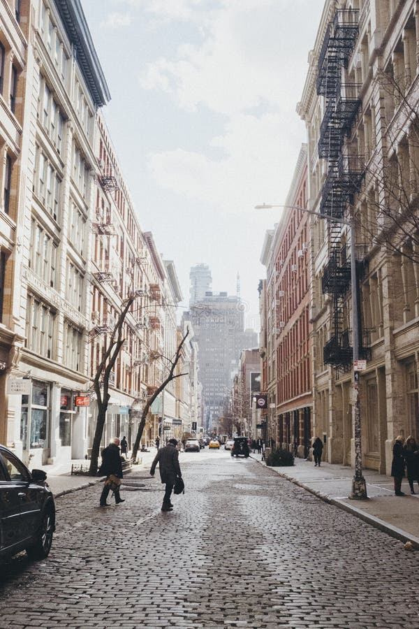 Vertical shot of people crossing a road between brown and white buildings stock photography Vertical shot of people crossing a road between brown and white buildings stock photography