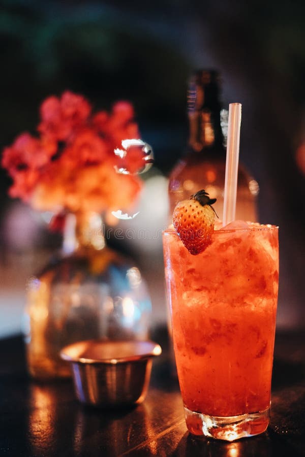 Vertical shot of a red drink with straws on the table with a blurred background.