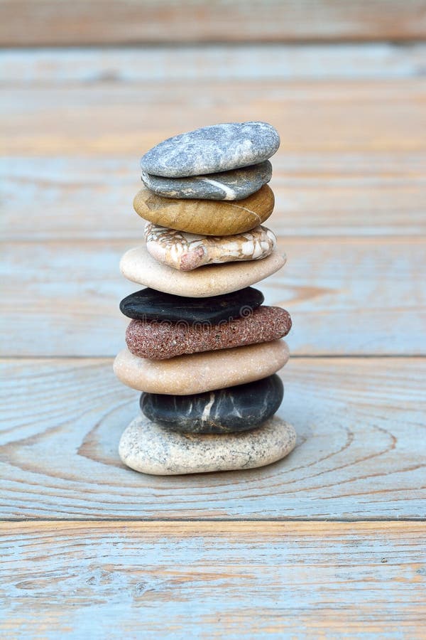 Vertical shot of a stack of flat stones on a wooden table royalty free stock images