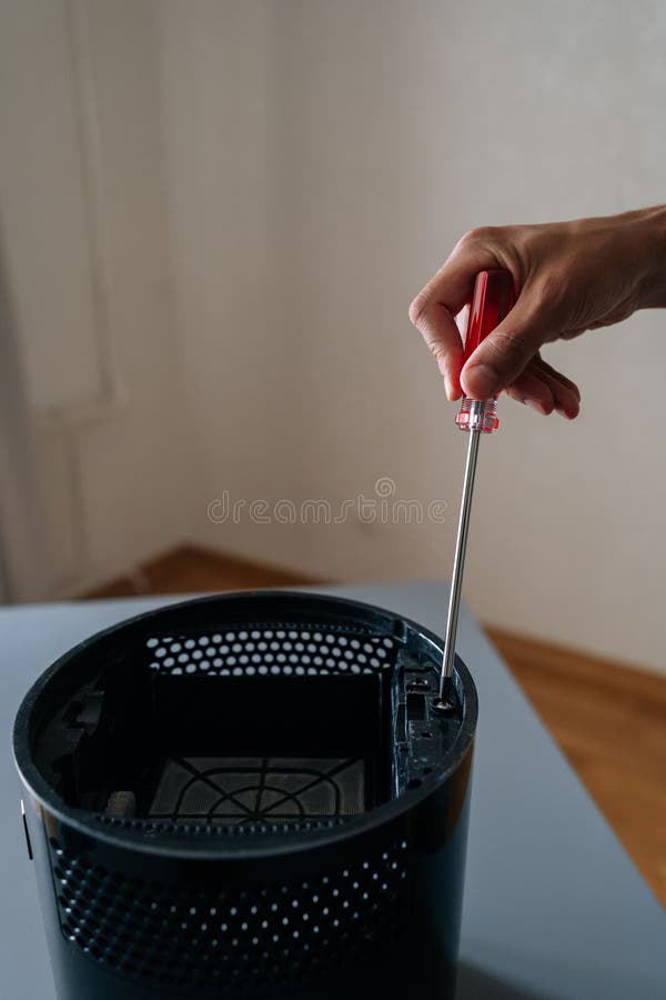 Vertical shot of technician hand using screwdriver to repair or maintain air humidifier, emphasizing importance of stock images