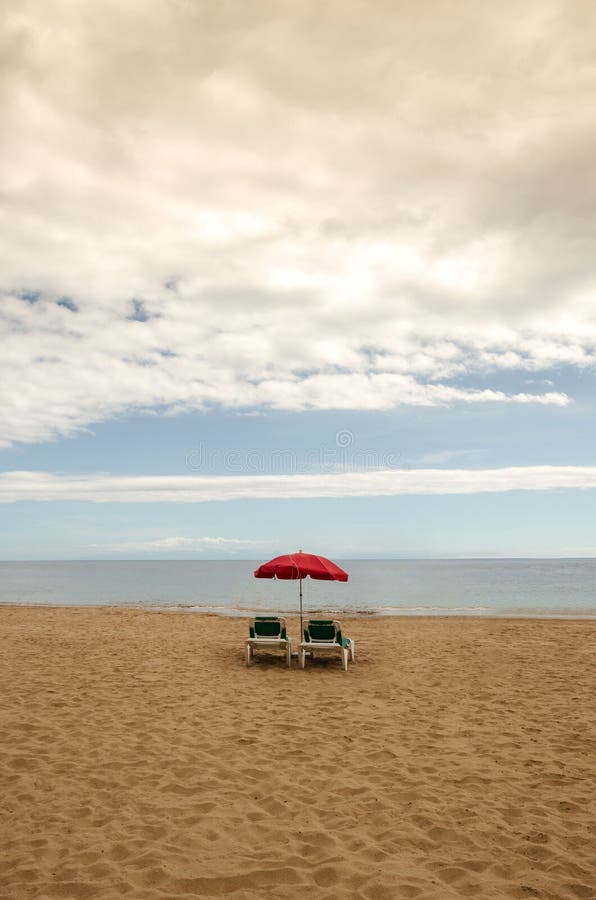 Vertical Shot of the Two Couches on the Sand of the Beach Stock Photo