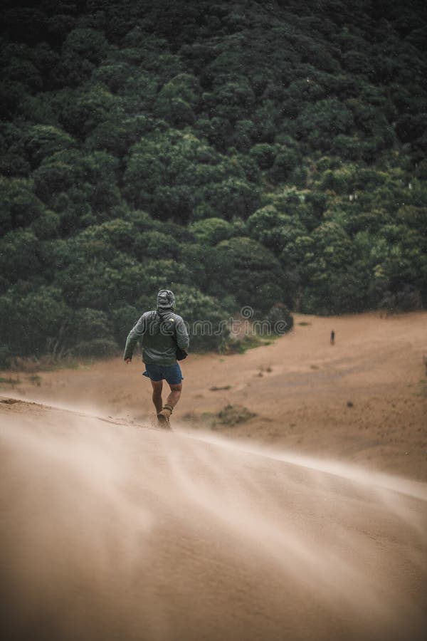 Vertical shot of an unrecognizable man running down by a sandy path on a mountain royalty free stock photos