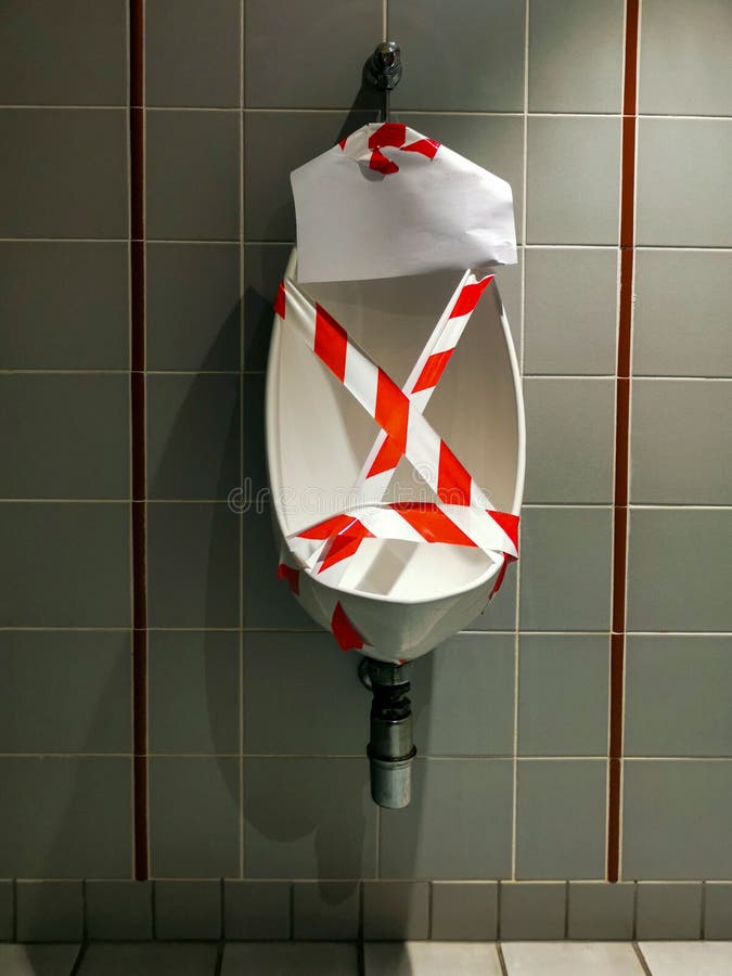 Vertical Shot of a Urinal for Men with a Barricade Tape Stock Photo