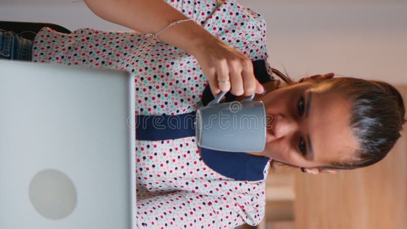 Vertical video: Tired lady working on laptop in the kitchen stock video footage