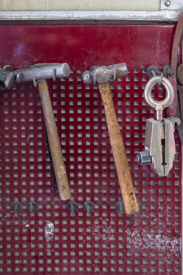 Vertical View of Two Old Hammers with a Brown Wooden Handle and a Clamp