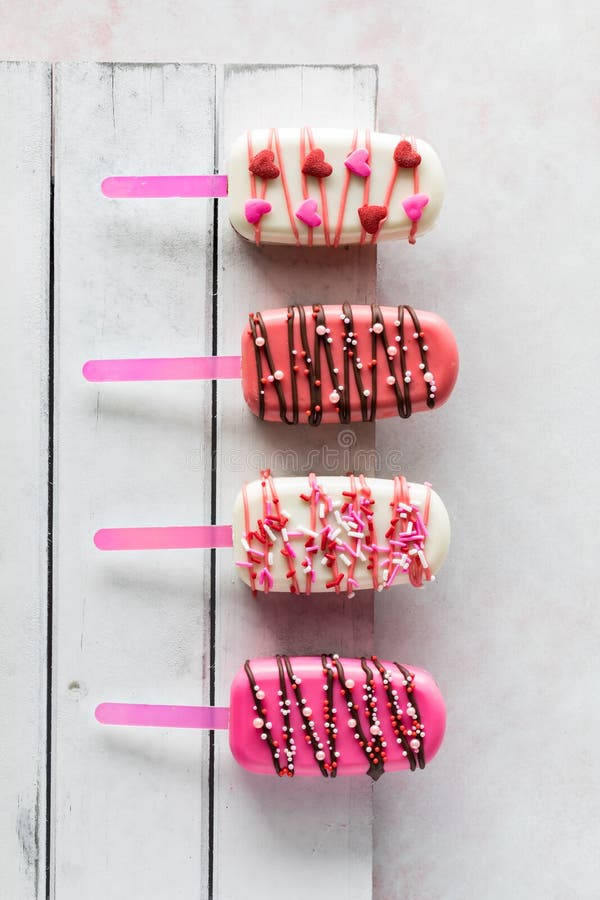 Vertical View of Valentine Cakesicles on a White Rustic Wooden Board