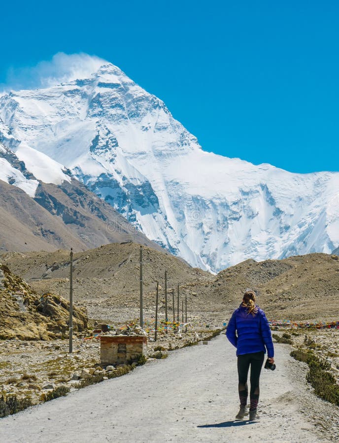 VERTICAL: Young female photographer walks down empty path leading to Everest. stock photos