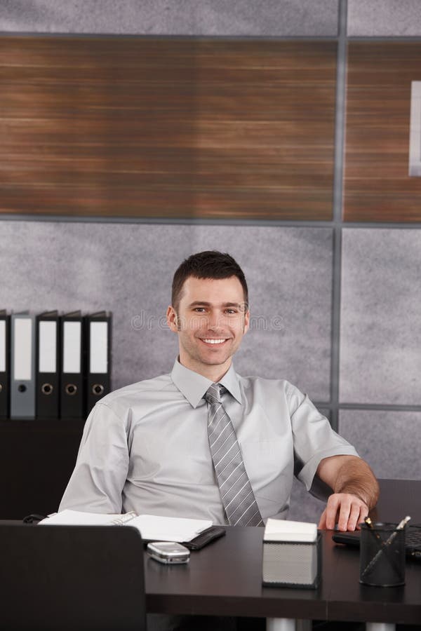 Portrait of casual businessman sitting at desk wearing short sleeved shirt, smiling. Copyspace above head. Portrait of casual businessman sitting at desk wearing short sleeved shirt, smiling. Copyspace above head.