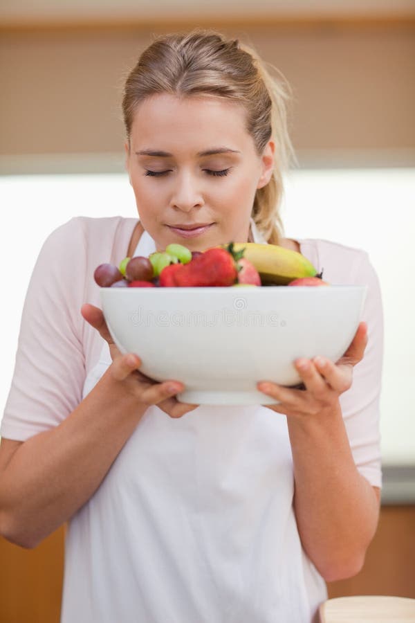 Verticale d'une jeune femme sentant un panier de fruit photographie stock libre de droits Verticale d'une jeune femme sentant un panier de fruit photographie stock libre de droits