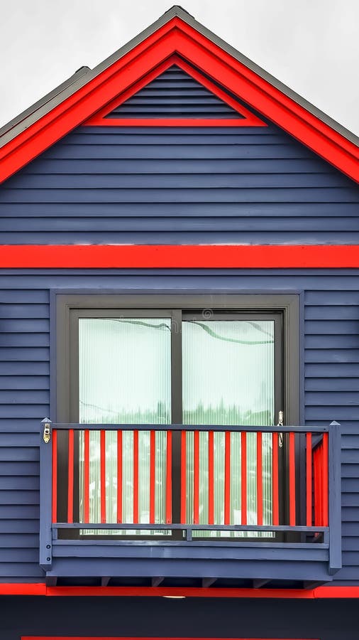 Verticale kader Dichte omhooggaand van huis buiten met trillende blauwe muur rode kaders en klein balkon royalty-vrije stock afbeeldingen Verticale kader Dichte omhooggaand van huis buiten met trillende blauwe muur rode kaders en klein balkon royalty-vrije stock afbeeldingen
