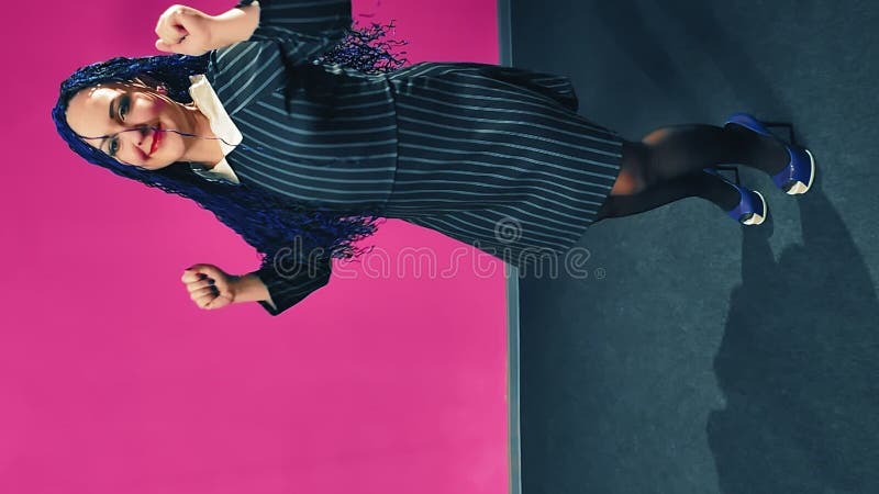 Vertically video woman with blue afro braids dancing on a pink background