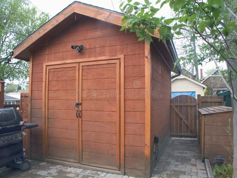 A two-door garden cedar tool shed in an urban back yard. A two-door garden cedar tool shed in an urban back yard.