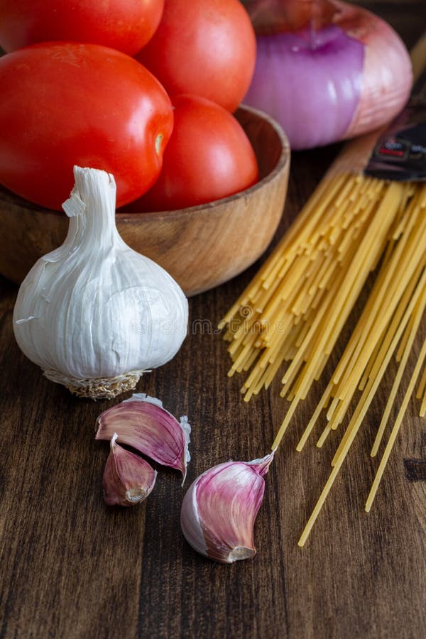 Vertikal bästa sikt av ingredienser för framställning av spagetti, av tomater, av vitlök och av lökar royaltyfri fotografi Vertikal bästa sikt av ingredienser för framställning av spagetti, av tomater, av vitlök och av lökar royaltyfri fotografi