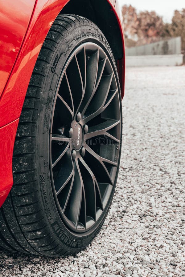 A vertical closeup of a MAK wheel with a Michelin tire parked on the gravel. A vertical closeup of a MAK wheel with a Michelin tire parked on the gravel