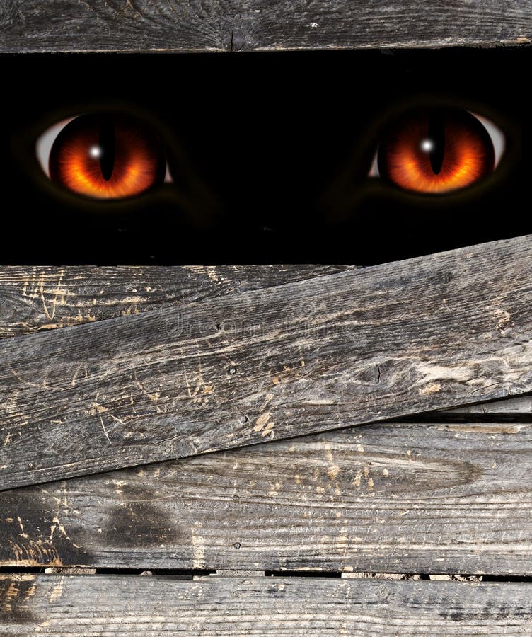Vertikaler Hintergrund mit alten Holzbrettern und rotes Auge des Monsters durch das Loch lizenzfreies stockbild