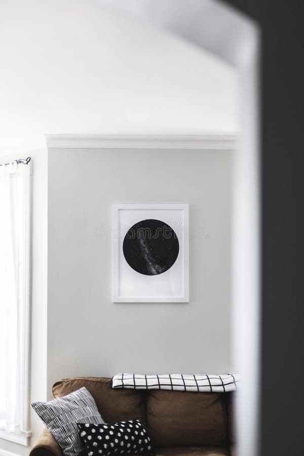 Vertikaler Schuss eines braunen Sofas mit Kissen und ein Schwarzweiss-Bild in einem Rahmen auf der Wand stockfotografie Vertikaler Schuss eines braunen Sofas mit Kissen und ein Schwarzweiss-Bild in einem Rahmen auf der Wand stockfotografie