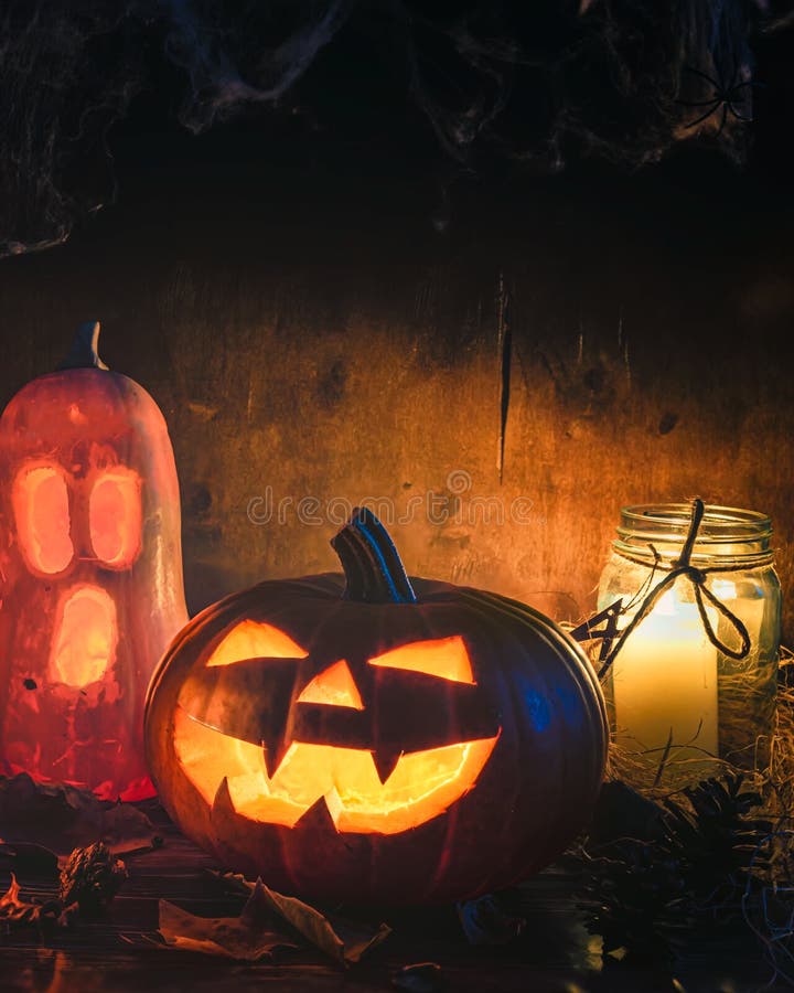 Vertikaler themenorientierter Hintergrund Halloweens, unheimliche Kürbise und Kerzen in einer dunklen Einstellung in einer Scheune