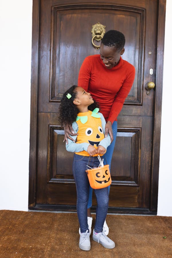 Vertikales Bild afrikanischer Mutter und Tochter in halloween Kostüm vor dem Haus stockbilder