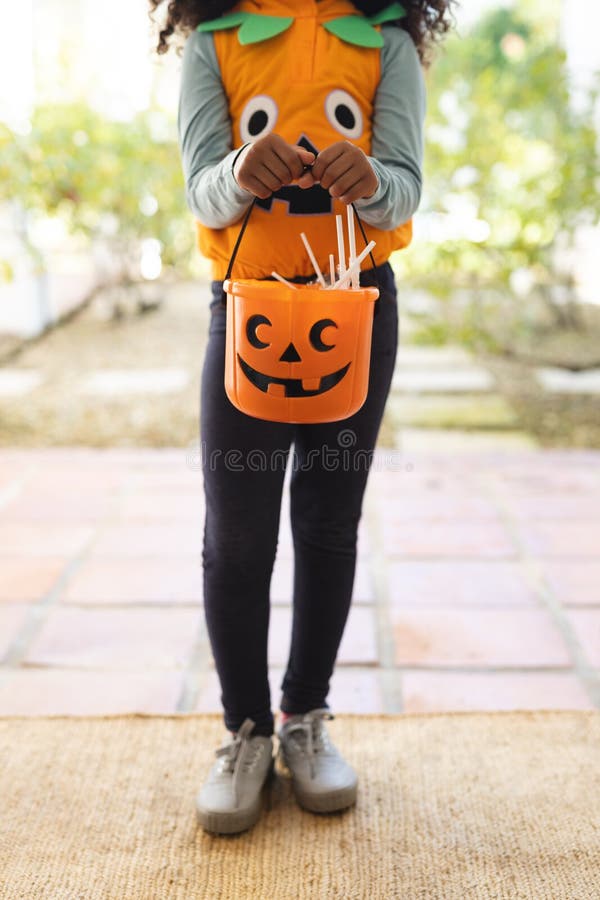 Vertikales Bild eines afrikanischen Mädchen in halloween Kostüm mit Korb stockbild