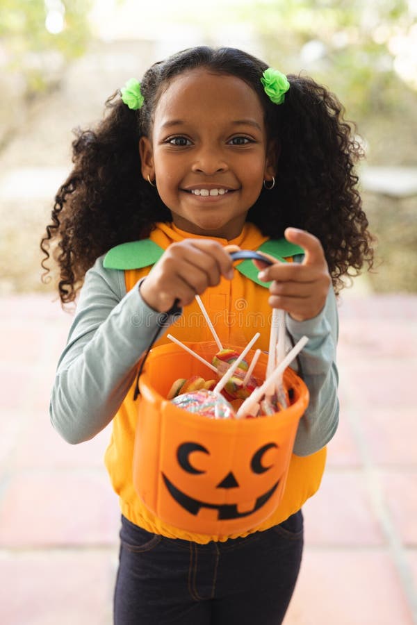 Vertikales Bild eines glücklichen afrikanischen amerikanischen Mädchens in halloween Kostüm mit Korb lizenzfreies stockbild