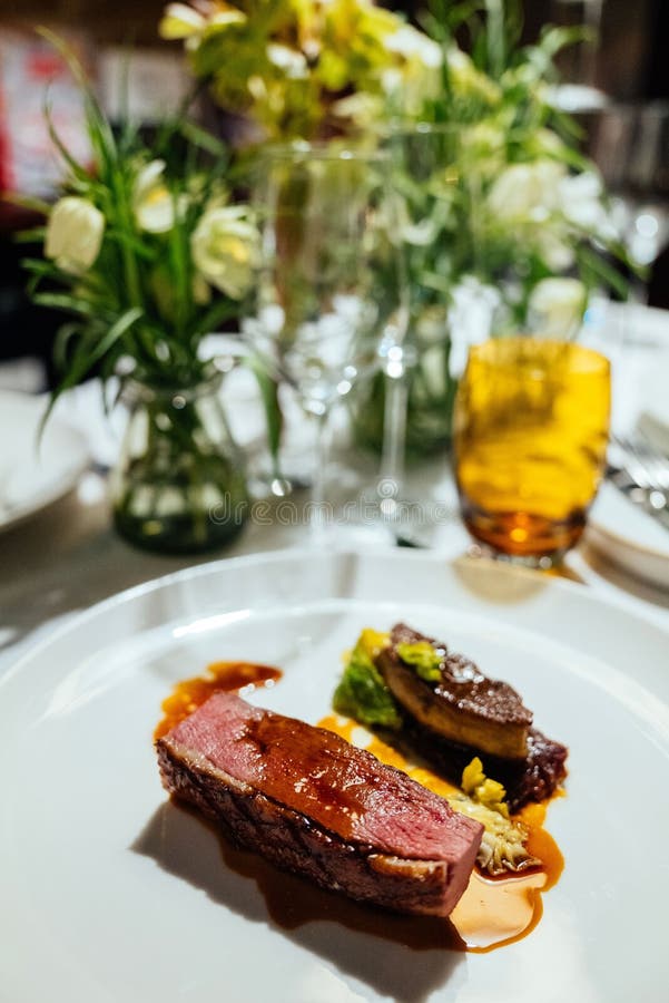 A vertical shot of a fine dinner in a Michelin restaurant in London with flowers in the background. A vertical shot of a fine dinner in a Michelin restaurant in London with flowers in the background