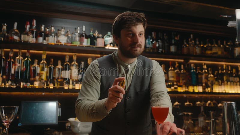 Vertrauter Barmann, der alkoholische Getränke in Cocktailglas an der Bar schmückt