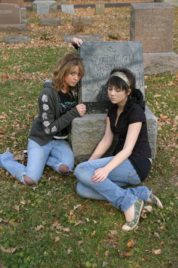 Teen girls sitting in cemetary by gravestone. Teen girls sitting in cemetary by gravestone