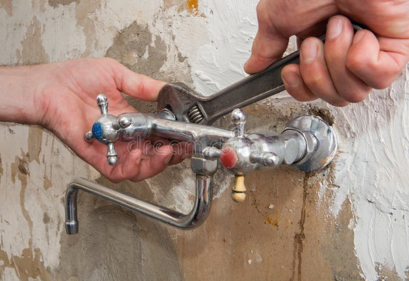 Fix a leaking tap, close-up of hands plumbing unscrew connecting nut wall faucet using an adjustable wrench. Fix a leaking tap, close-up of hands plumbing unscrew connecting nut wall faucet using an adjustable wrench.