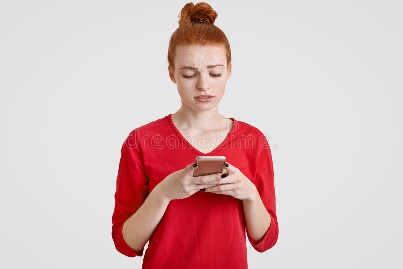 Verwirrte sommersprossige junge Frau mit dem natürlichen roten Haar, das im Knoten gebunden wird, trägt zufälliges Hemd, schaut i stockfotos Verwirrte sommersprossige junge Frau mit dem natürlichen roten Haar, das im Knoten gebunden wird, trägt zufälliges Hemd, schaut i stockfotos