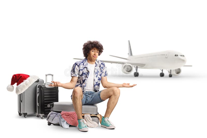 Verwirrter männlicher Tourist, der auf einem Koffer vor einem Flugzeug sitzt stockfotografie