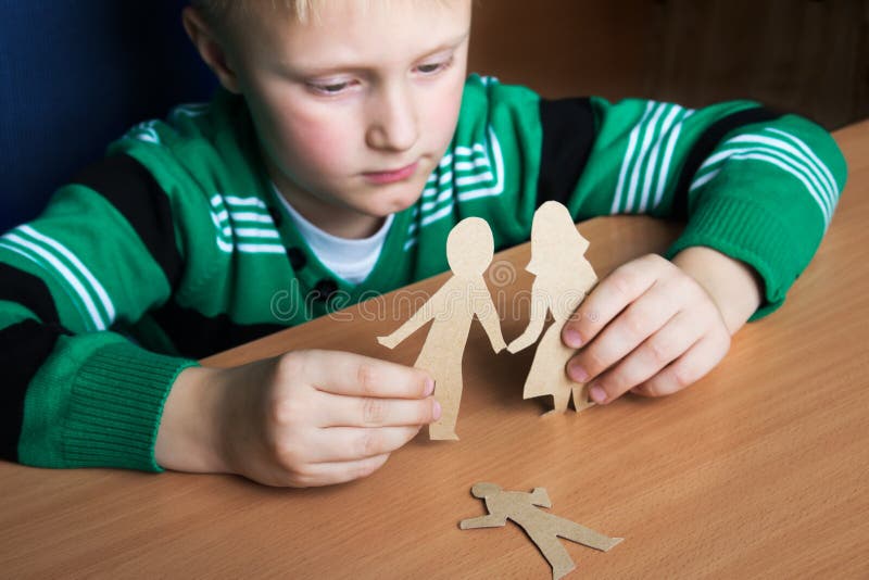Verwirrtes Kind mit Papierfamilie lizenzfreie stockfotos Verwirrtes Kind mit Papierfamilie lizenzfreie stockfotos