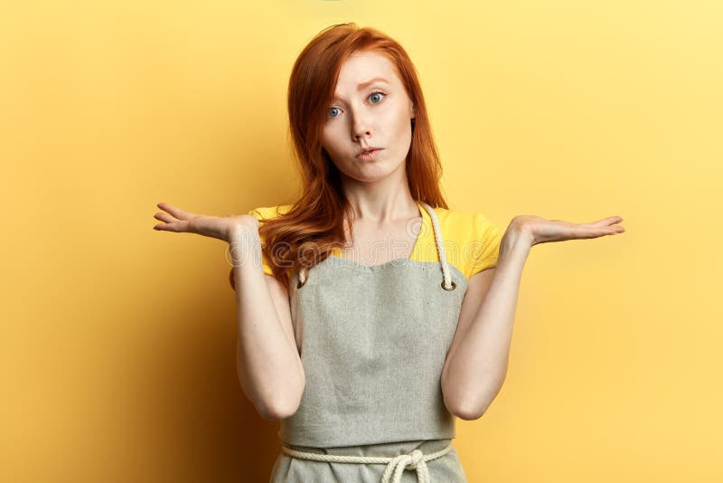 Verwirrtes zögerndes Mädchen mit dem langen roten Haar im grauen Schutzblech und im T-Shirt lizenzfreies stockfoto Verwirrtes zögerndes Mädchen mit dem langen roten Haar im grauen Schutzblech und im T-Shirt lizenzfreies stockfoto