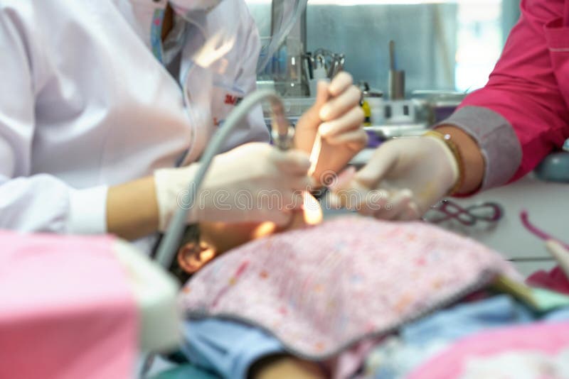 Verwischen Sie Foto von Zahnarztarbeitszimmerreparatur-Kinderzähnen mit Assistenten stockfotos Verwischen Sie Foto von Zahnarztarbeitszimmerreparatur-Kinderzähnen mit Assistenten stockfotos