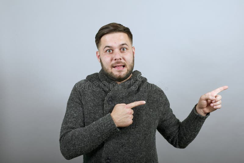 Verworrene männliche Showzeigefingerrichtung verzog Gesicht. das Konzept der überrascht stockbild