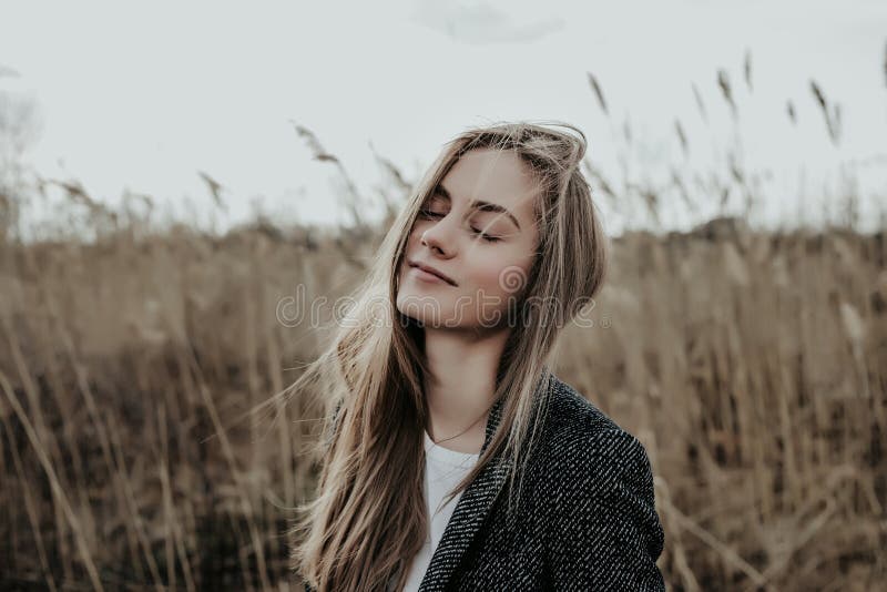 Very beautiful and fashion girl with closed eyes standing on bulrush background. royalty free stock image Very beautiful and fashion girl with closed eyes standing on bulrush background. royalty free stock image