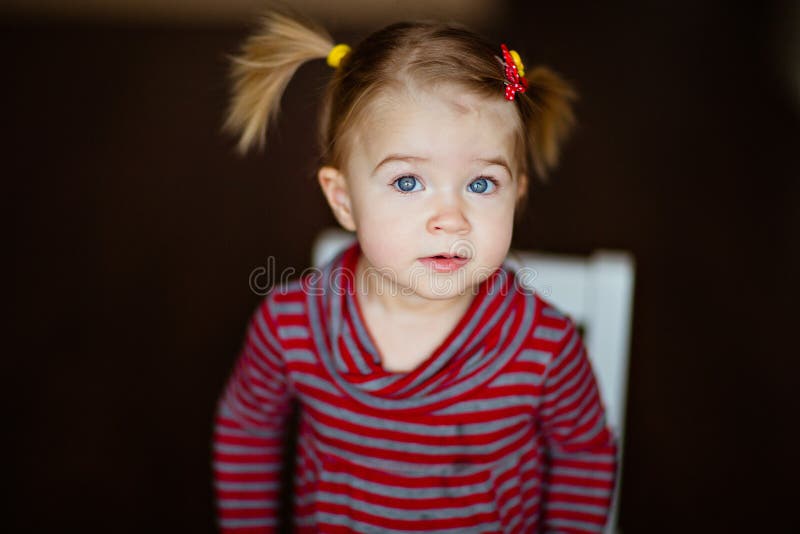 Very cute little girl in a striped dress sitting on a chair stock images Very cute little girl in a striped dress sitting on a chair stock images