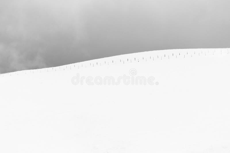 A very minimalistic view of a mountain covered by snow, with a fence