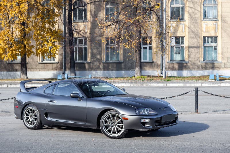 Novosibirsk, Russia - 10.09.2019: A very rare Japanese sports car in the back of a Toyota Supra coupe in gray with a high spoiler on the road in the city near trees with yellow leaves