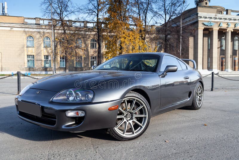 Novosibirsk, Russia - 10.09.2019: A very rare Japanese sports car in the back of a Toyota Supra coupe in gray with a high spoiler on the road in the city near trees with yellow leaves